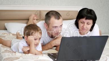 幸福家庭：<strong>爸爸妈妈</strong>和儿子躺在床上看着笔记本电脑屏幕。